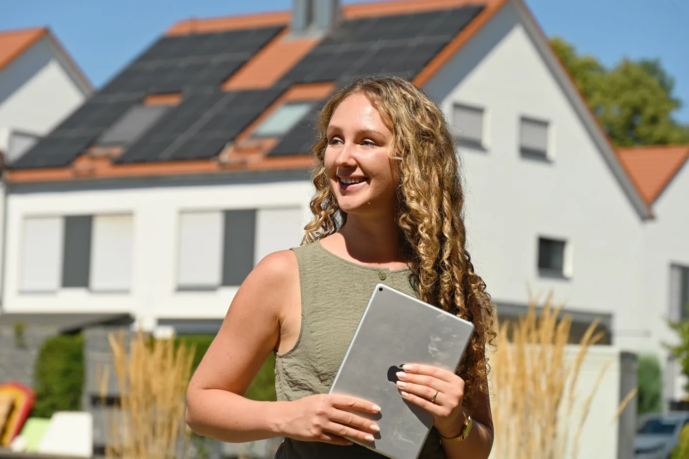 Emma Hippert mit Tablet vor einem Reihenhaus