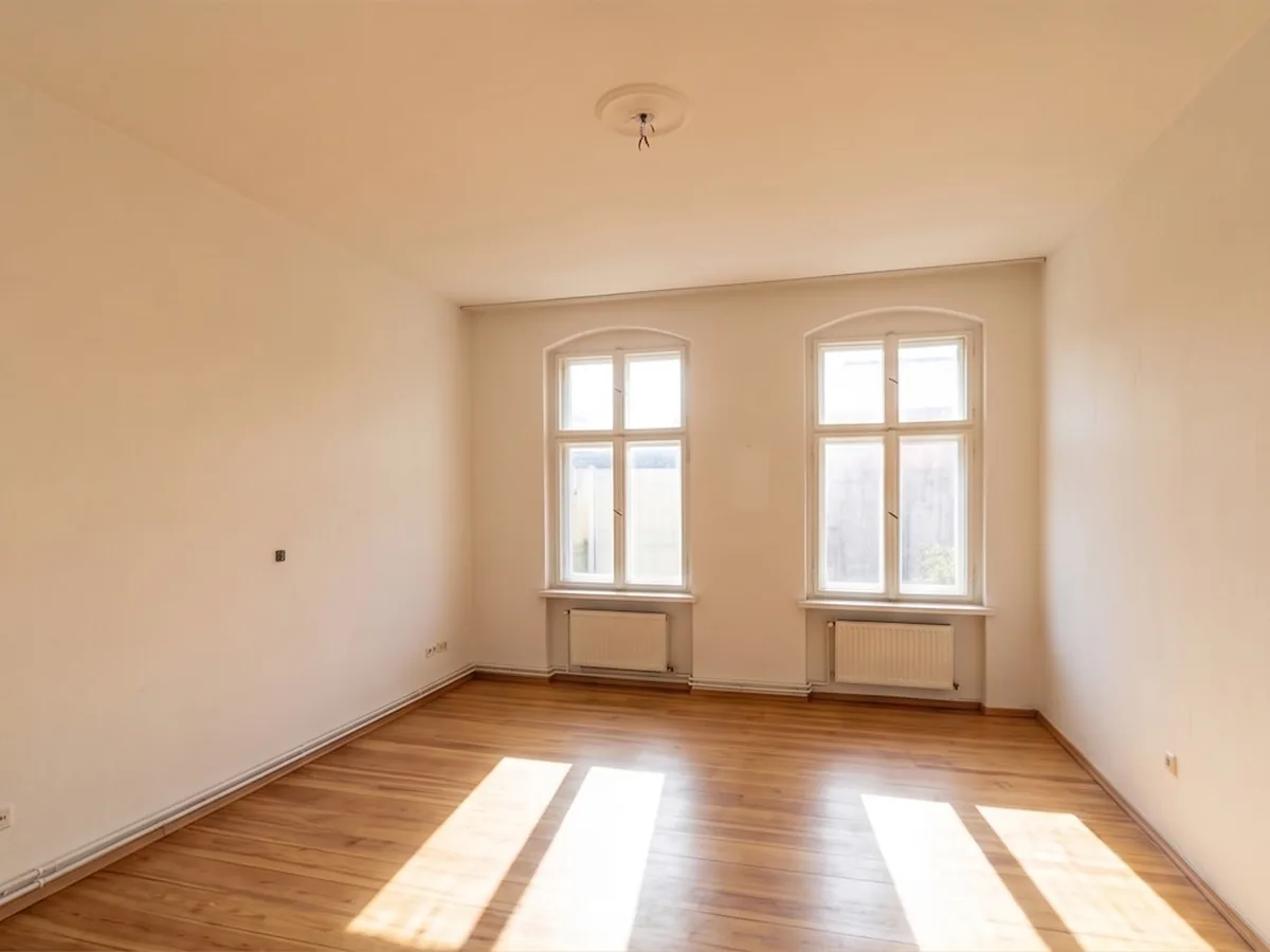 Leergeräumtes Zimmer im Altbau mit Holzdielen und zwei Sprossenfenstern