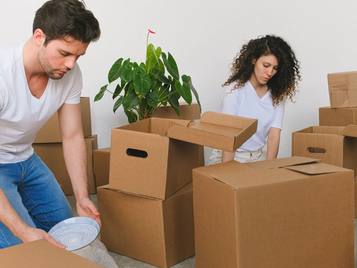 Zwei Menschen packen Umzugskartons
