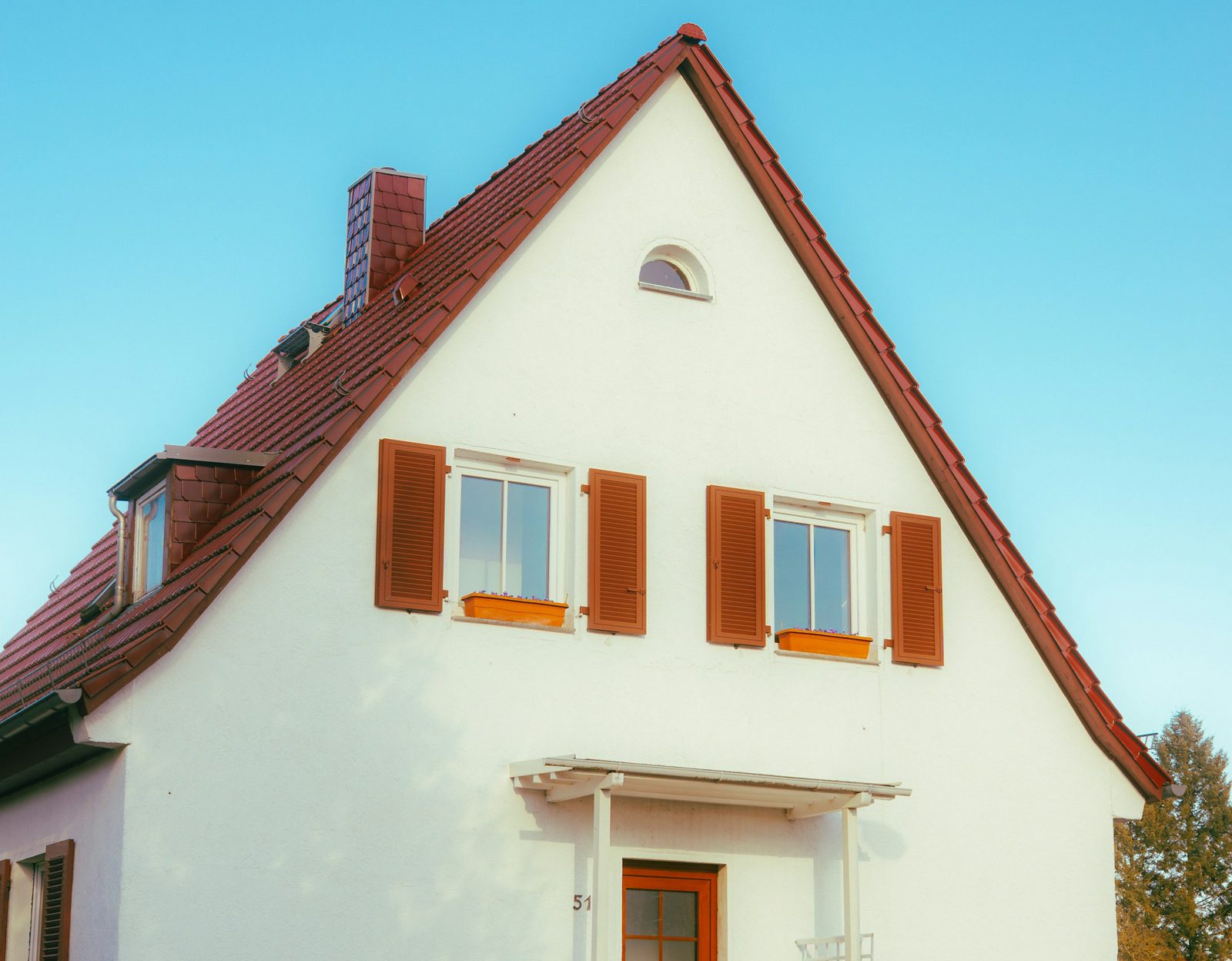 Weißes Haus mit rotem Dach und Fensterläden